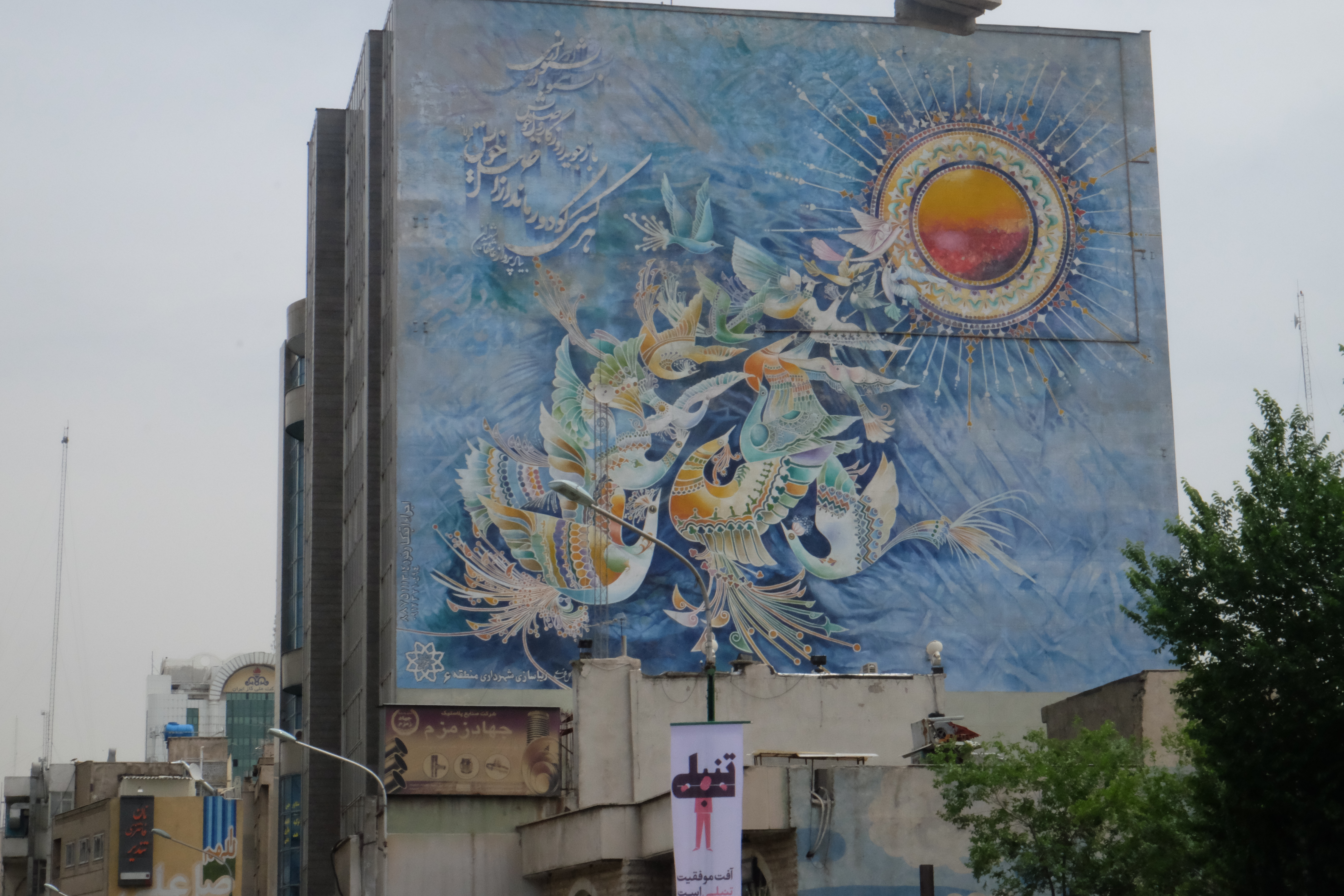 Wandbild auf einer Hausmauer in Teheran, auf dem Vögel zu sehen sind, die in das Sonnelicht fliegen