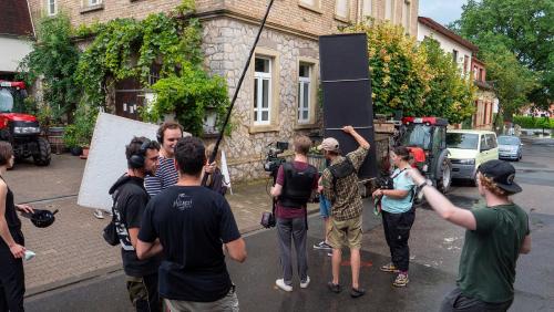 Eine Gruppe Menschen steht mit Filmequipment auf einer Straße.